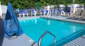 a swimming pool with blue chairs and an umbrella at Days Inn by Wyndham Ocean Springs in Ocean Springs