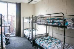 two bunk beds in a room with a window at Barkly Backpackers in Melbourne
