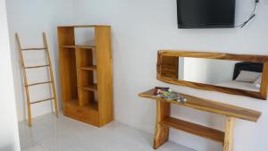 a room with a tv and a wooden shelf at Jingga Homestay Balangan in Jimbaran