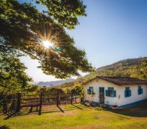 a house with a fence and the sun in the sky at Sítio Lavras do Abade in Pirenópolis