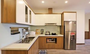 uma cozinha com um frigorífico de aço inoxidável e armários de madeira em Luxe Paradise Residence Tay Ho em Hanói