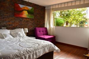 a bedroom with a bed and a pink chair at Casa Iris in Chía