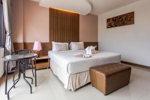a hotel room with a bed and a table and a chair at The Centris Hotel Phatthalung in Phatthalung