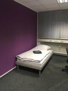 Bett in einem Zimmer mit lila Wänden in der Unterkunft Hostel Hamm by Geronimo in Hamm