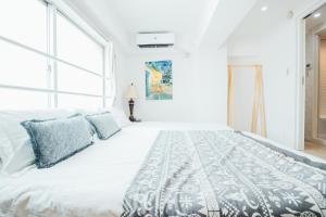 a white bedroom with a large bed with blue pillows at 横浜元町 in Yokohama