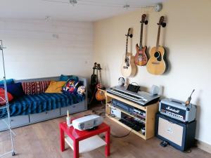 een woonkamer met een bank en gitaren aan de muur bij Tipergwendiou in Plougonvelin