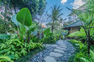 a garden with a stone path in front of a house at D'Junas Villas by GenuineHost in Ubud