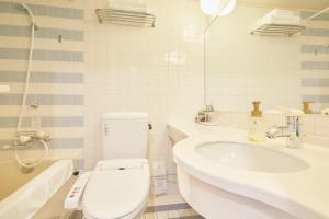 a white bathroom with a toilet and a sink at Hotel Seagull Tenpozan Osaka in Osaka