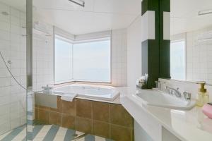 a bathroom with a tub and a sink and a window at Hotel Seagull Tenpozan Osaka in Osaka