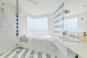 a white bathroom with two sinks and a window at Hotel Seagull Tenpozan Osaka in Osaka