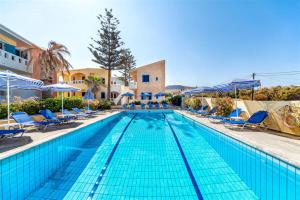 a large swimming pool with blue chairs and umbrellas at Niros Beachfront Aparthotel in Kokkíni Khánion