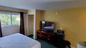 Schlafzimmer mit einem Bett und einem Flachbild-TV in der Unterkunft Comox Valley Inn & Suites in Courtenay