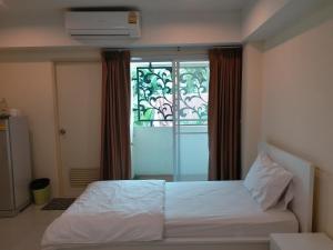 1 dormitorio con cama blanca y ventana en TongPrasit Place, en Nakhon Ratchasima