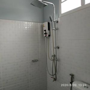 uma cabina de duche na casa de banho com azulejos brancos em เรือนวรา - Wara Guesthouse em Nan