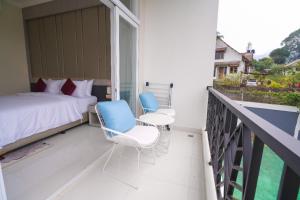 a bedroom with a bed and two chairs on a balcony at Marseillia Hills in Puncak