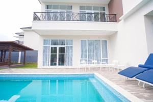 a villa with a swimming pool in front of a house at Marseillia Hills in Puncak