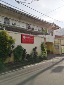 a building with a red sign on the side of a street at RedDoorz near SM Batangas City in Batangas City