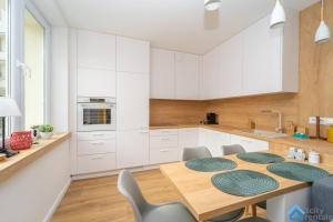una cucina con tavolo in legno e armadietti bianchi di Scandinavian Gdynia a Gdynia