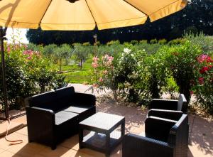 un patio con 2 sillas y una sombrilla en Agriturismo Monteroseo, en bedizzol