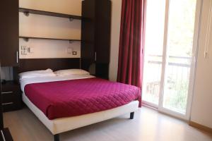 a bedroom with a bed and a large window at Hotel Morolli in Rimini