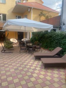 阿德列爾的住宿－塔拉索旅館，庭院配有白色遮阳伞和桌椅。