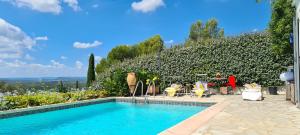 a swimming pool in front of a hedge with chairs and tables at Corniche du Paradis in Roquebrune-sur-Argens