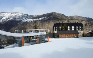 a building in the snow in front of a mountain at Hotel Or Blanc in Espot