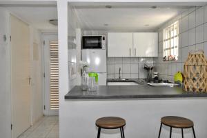 una cocina con armarios blancos y 2 taburetes en Seru Coral Apartment, en Willemstad