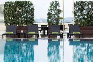a swimming pool with two chairs and a table and a table at Centara Riverside Hotel Chiang Mai in Chiang Mai