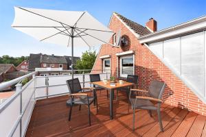 - un balcon avec une table, des chaises et un parasol dans l'établissement Ferienwohnung Teezeit, à Neuharlingersiel