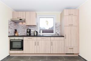 a kitchen with wooden cabinets and a window at Ferienwohnung Teezeit in Neuharlingersiel