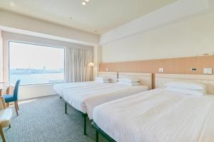 two beds in a hotel room with a large window at Hotel Seagull Tenpozan Osaka in Osaka