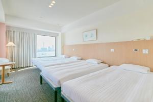 a row of beds in a room with a window at Hotel Seagull Tenpozan Osaka in Osaka
