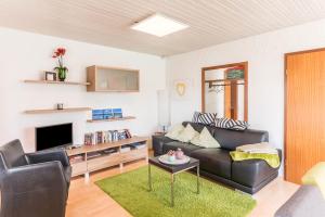 a living room with a black leather couch and a tv at Appartement Böhler 1 in Reichenau
