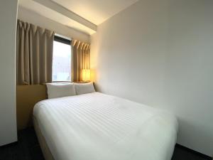 a white bed in a room with a window at Santiago Hotel in Hiroshima