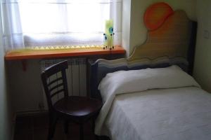 a bedroom with a bed and a chair and a window at APARTAMENTO LAS ERAS in Hontanares
