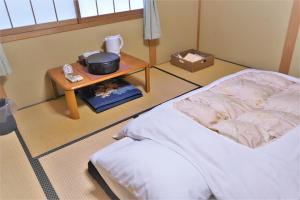 a room with a bed and a table with a pot on it at Ryokan Shimizu in Kyoto