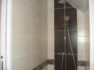 La salle de bains est pourvue d'une douche avec une porte en verre. dans l'établissement Ti Bihan - Meublé, à Santec
