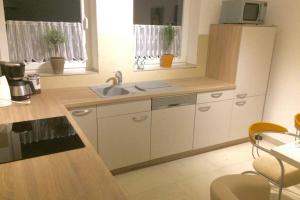 Una cocina con gabinetes blancos y un fregadero. en Elegantes Haus im Dresdner Süden, en Bannewitz