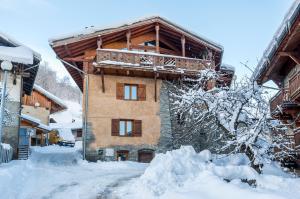 un bâtiment avec un balcon dans la neige dans l'établissement La Portette Chambres d'Hôtes, à Bellentre