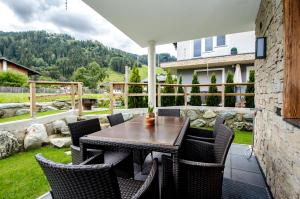 an outdoor patio with a wooden table and chairs at Kitz Juwel Top 2 in Hollersbach im Pinzgau