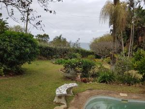 a backyard with a swimming pool and a stone bench at Fairway cottage in Port Edward
