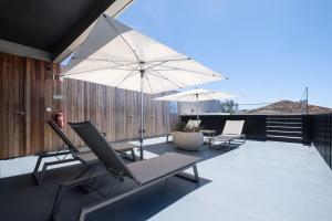 eine Terrasse mit 2 Stühlen und einem Sonnenschirm in der Unterkunft Aqua - Pópulo Eco Village in Ponta Delgada