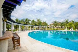 a pool at the resort with chairs and palm trees at Seava Ho Tram Beach Resort in Ho Coc