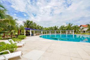 a pool at a resort with palm trees at Seava Ho Tram Beach Resort in Ho Coc