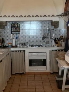 cocina con fogones y horno blanco en Dammuso Oriente en Pantelleria