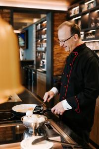 a man in a kitchen preparing food in a pan at Gästeappartements Sonnenland in Sankt Englmar