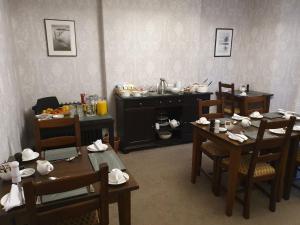 a dining room with tables and chairs and a kitchen at Strathmore Guest House in Keswick