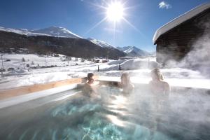 three women in a hot tub in the snow at Mont Chalet Nevada - Hotel & Spa in Livigno