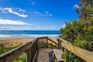 a wooden boardwalk to the beach with the ocean at Diamond Beach Resort, Mid North Coast NSW in Diamond Beach